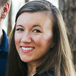 A man and woman smiling in front of a tree.