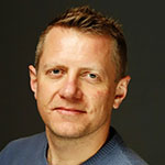 A man in a blue sweater is posing for a picture.