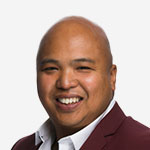 A man in a maroon suit smiling for the camera.