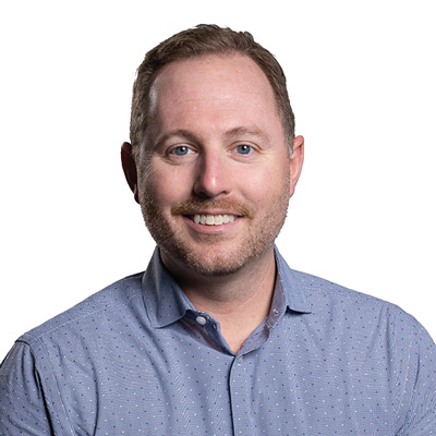 A man in a blue shirt smiling for the camera.