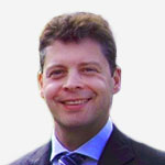 A man in a suit and tie smiling for the camera.