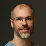 A man wearing glasses and a blue shirt.