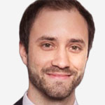 A man in a suit and tie is smiling.