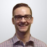 A smiling man wearing glasses and a plaid shirt.