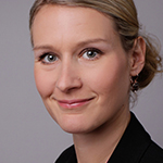 A woman in a black jacket is smiling at the camera.