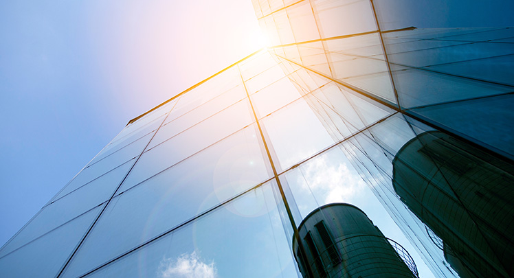 Blick nach oben auf ein hohes Gebäude mit Glaswänden