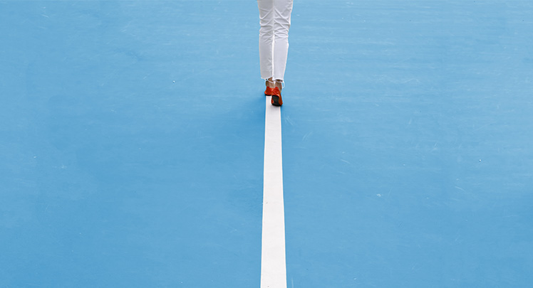 A woman is walking on a tennis court.