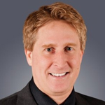 A man in a suit and tie smiles for the camera.