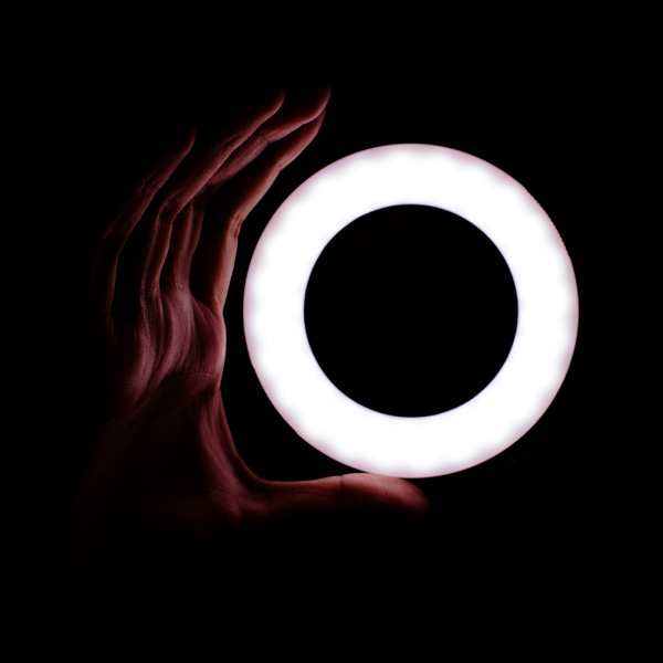 A person's hand holding up a circular light.